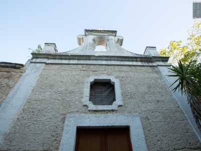...con finestrella centrale dominata da un cornicione in pietra che culmina con un piccolo campanile decorato a volute